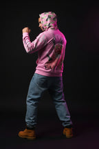 Person wearing a pink hoodie with graphic designs in a neon-lit room