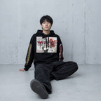 Model wearing the Vazzari Trauma Bonding Hoodie – Noir in a beige studio
