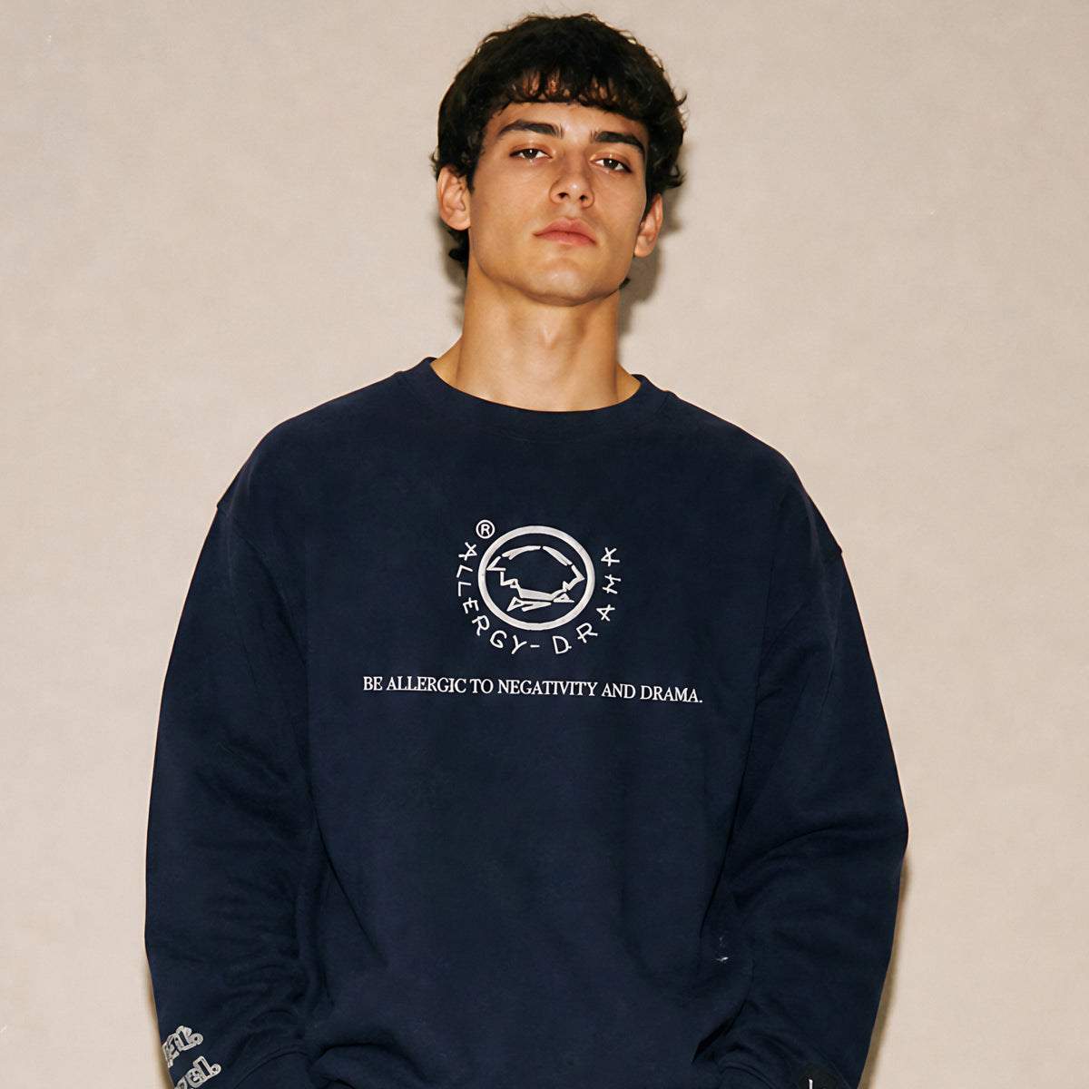 Model wearing the Vazzari Vibrate Higher Sweatshirt – Navy in a beige studio